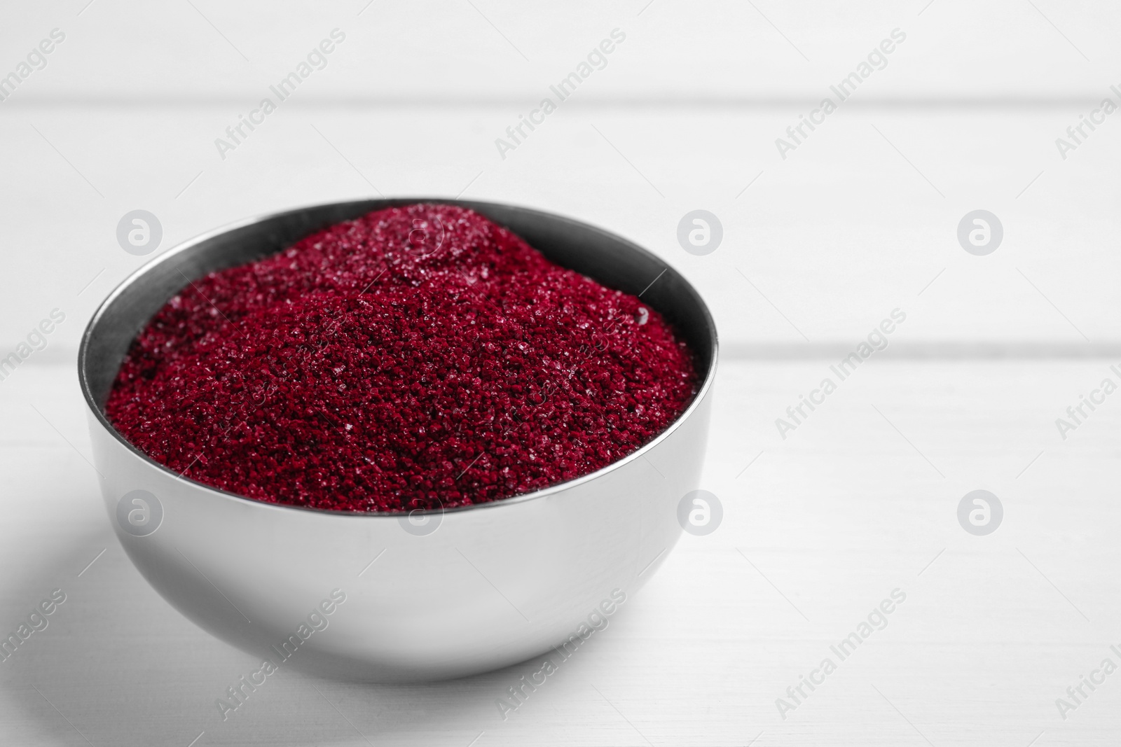 Photo of Bowl with dark red food coloring on white table, closeup. Space for text