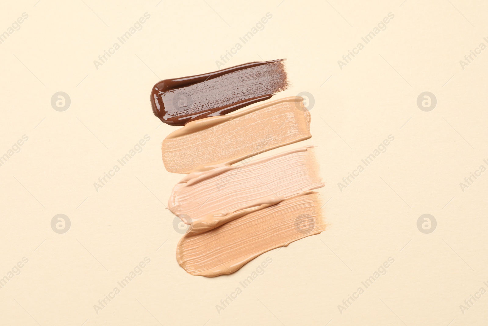 Photo of Samples of skin foundation on beige background, top view