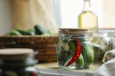 Jar of pickled cucumbers on wooden table, closeup. Space for text