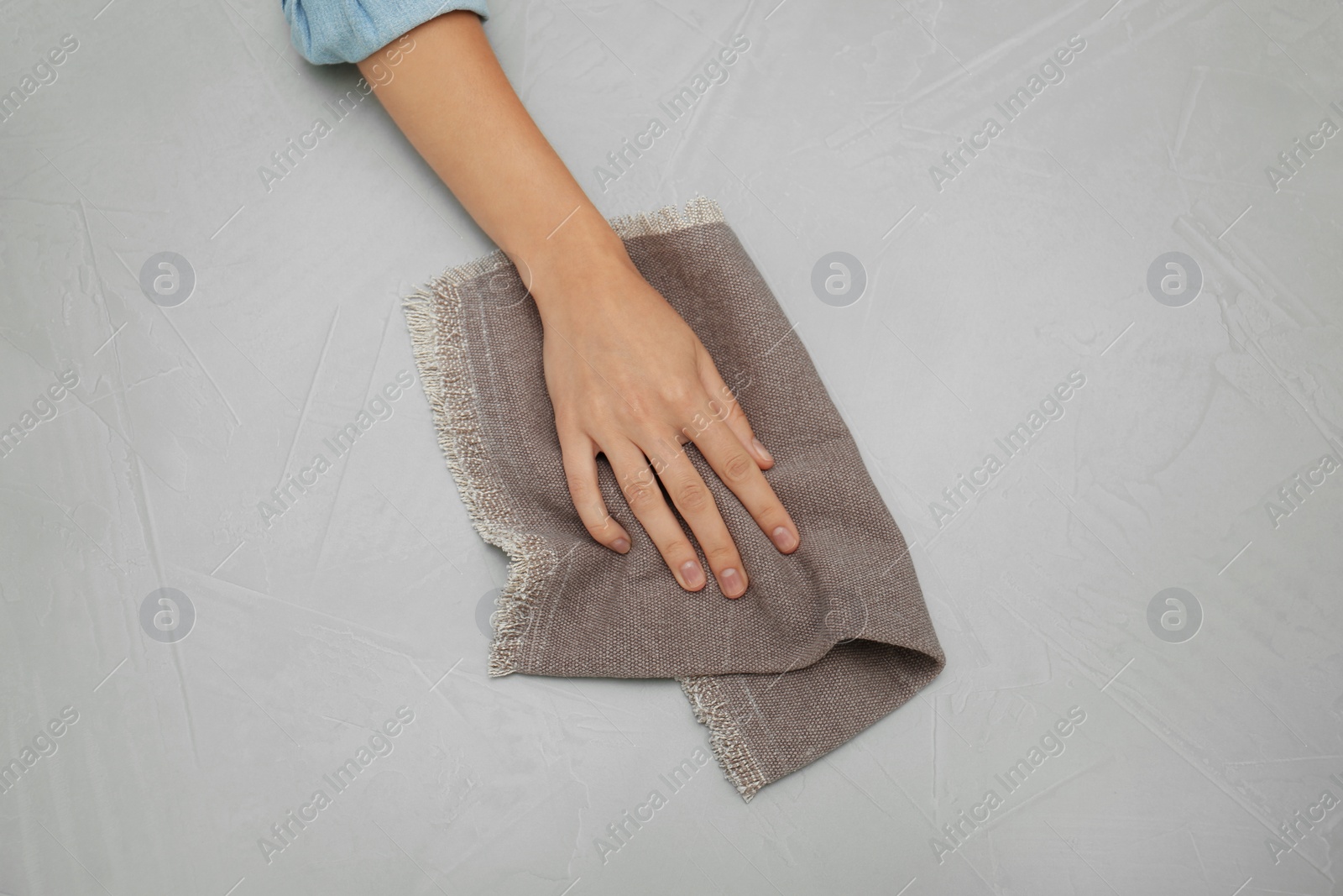Photo of Woman wiping grey table with kitchen towel, top view