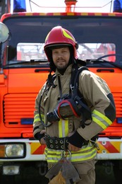 Photo of Portrait of firefighter in uniform near fire truck outdoors