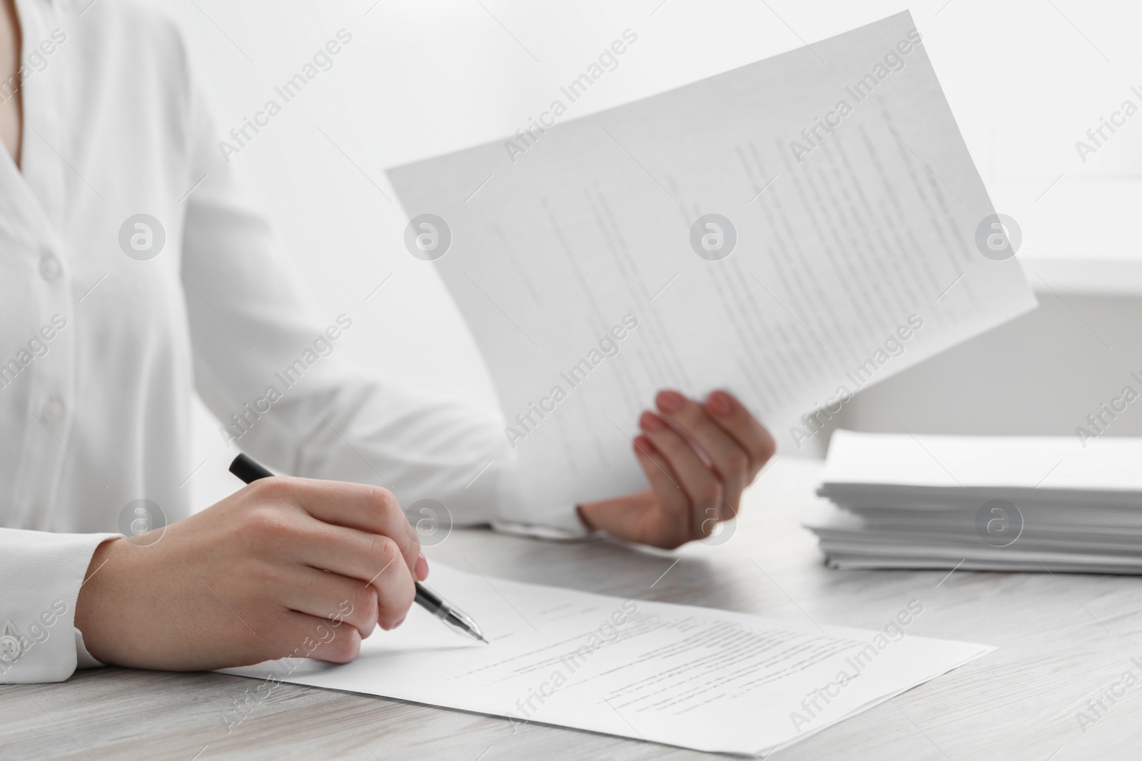 Photo of Woman signing documents at wooden table in office, closeup