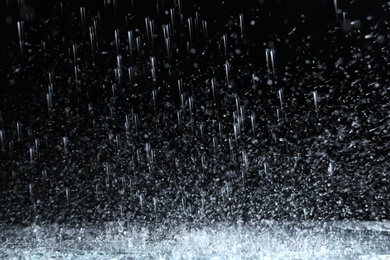 Photo of Heavy rain falling down on ground against dark background