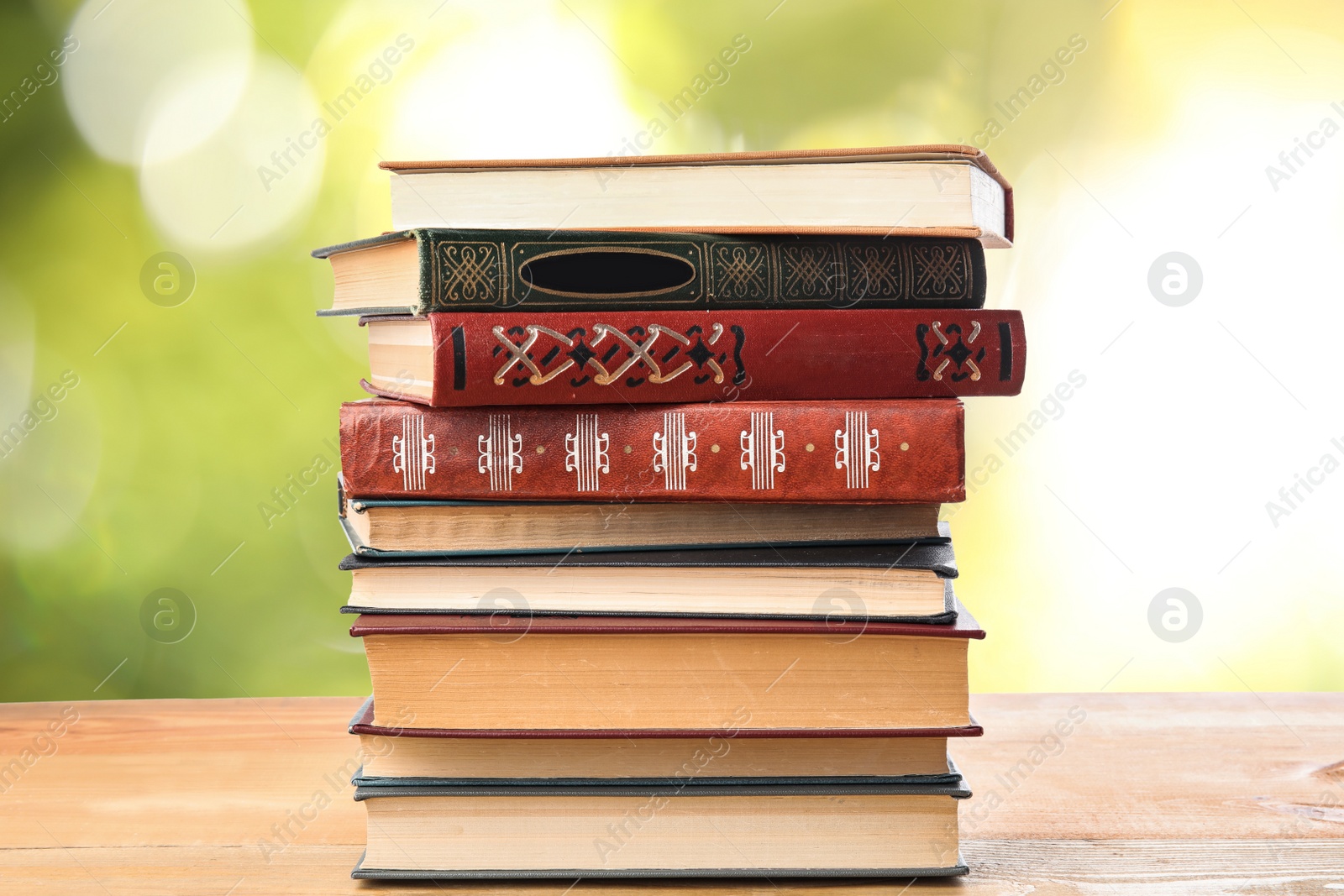 Image of Collection of different books on wooden table against blurred green background