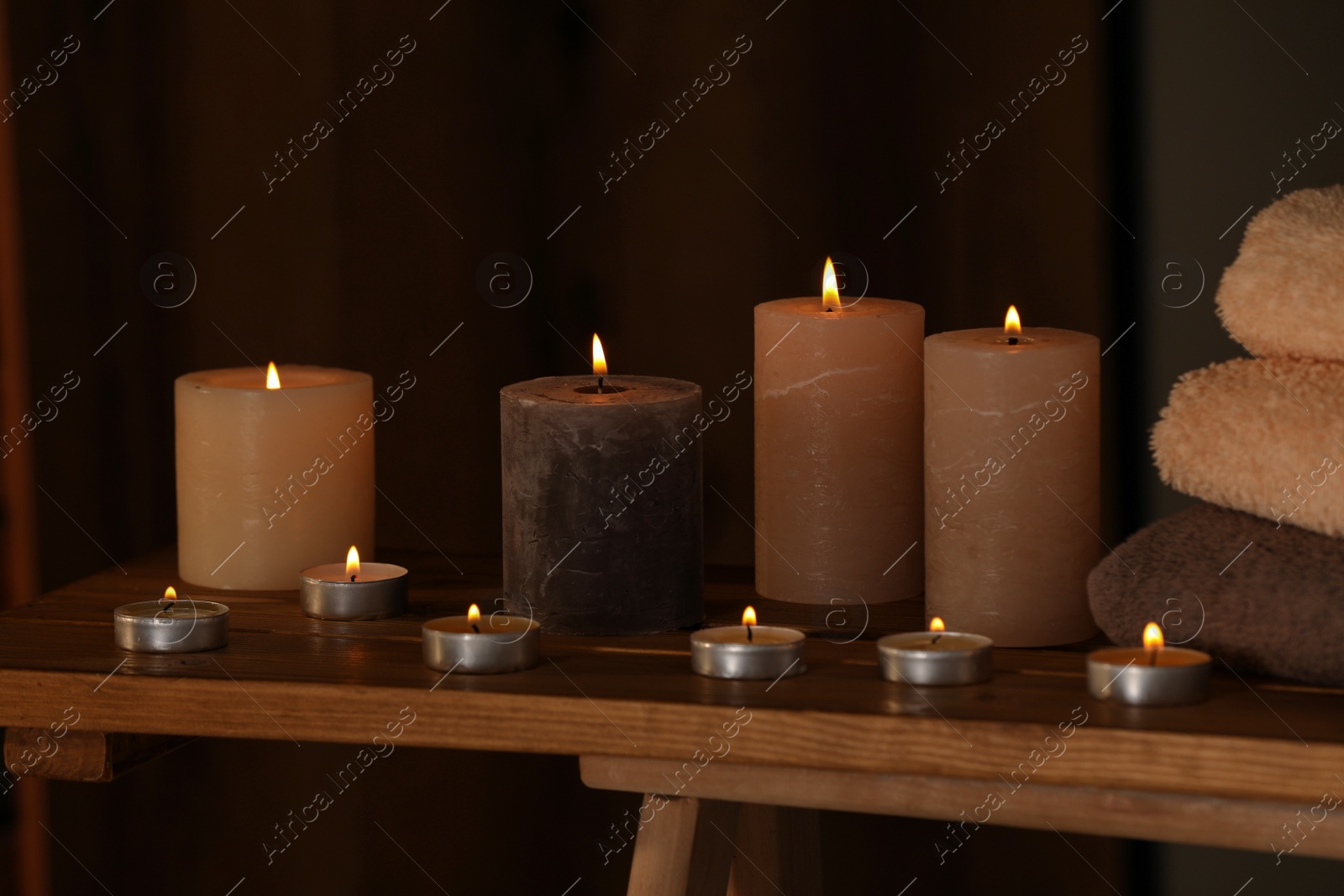 Photo of Spa composition with burning candles and towels on wooden table in wellness center