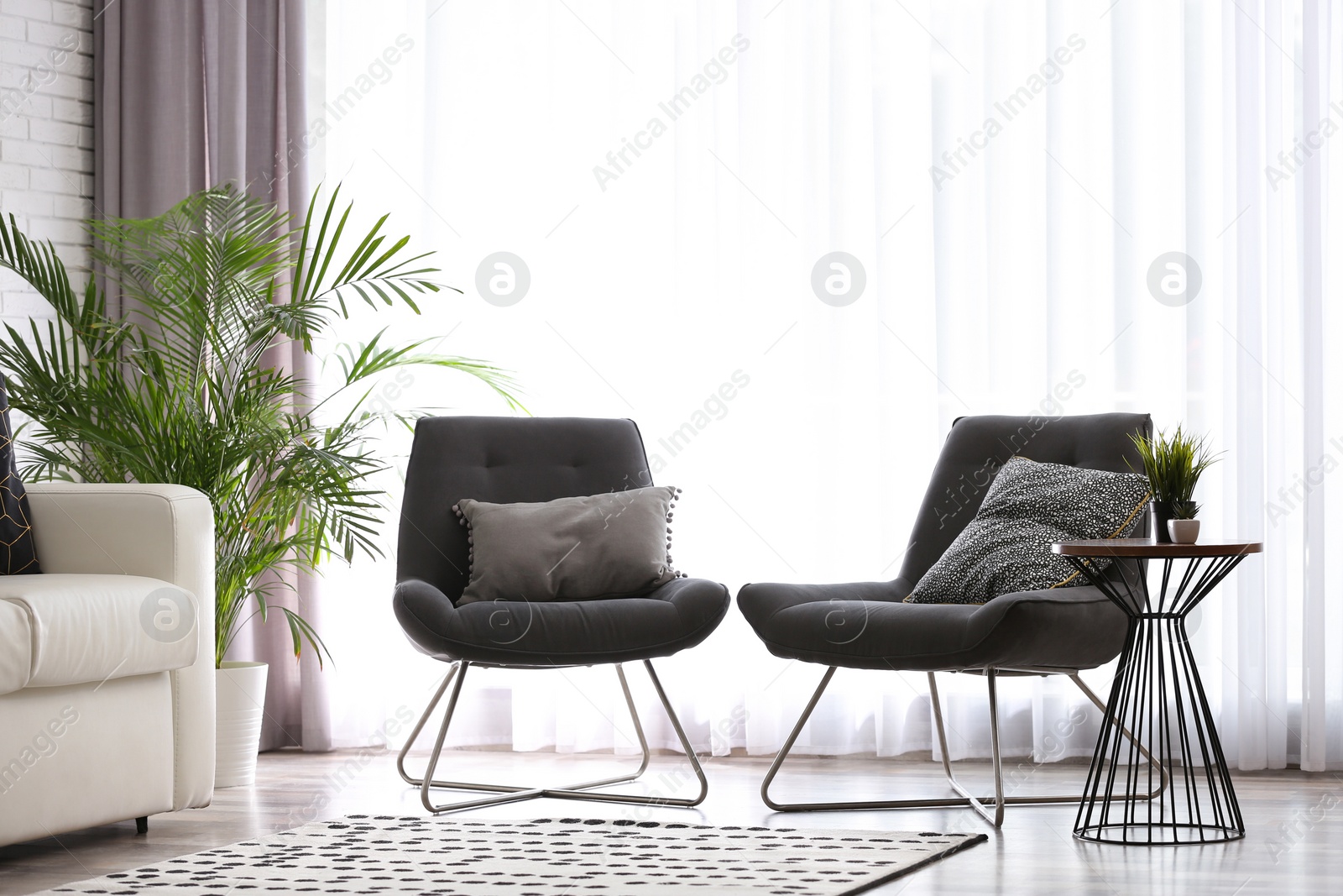 Photo of Comfortable sofa and chairs near window with elegant curtains in room