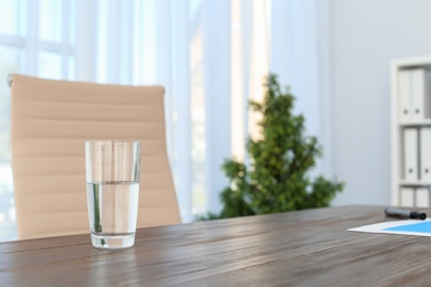 Photo of Glass of water on table in office. Space for text