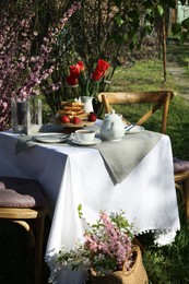 Photo of Beautiful bouquet of tulips and freshly baked waffles on table served for tea drinking in garden