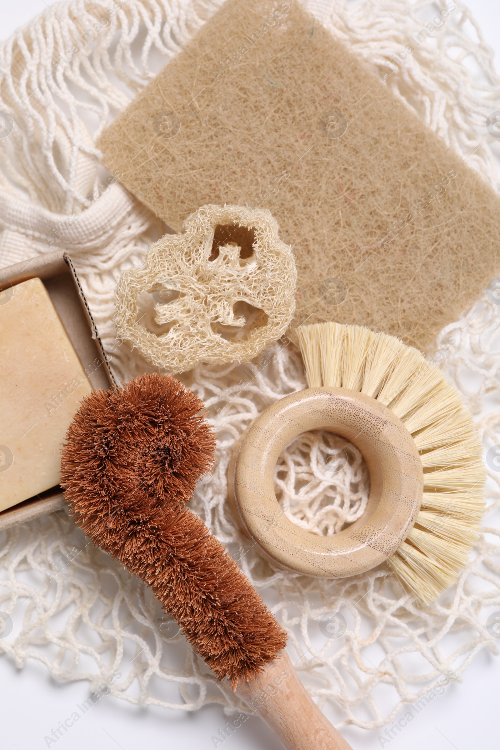 Photo of Cleaning brushes, sponge, loofah and soap bar on white table, top view