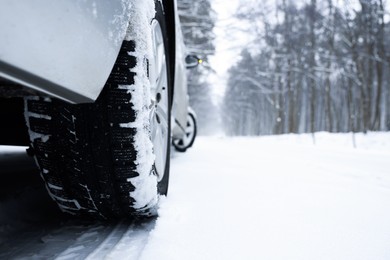 Photo of Car with winter tires on snowy road in forest, closeup. Space for text