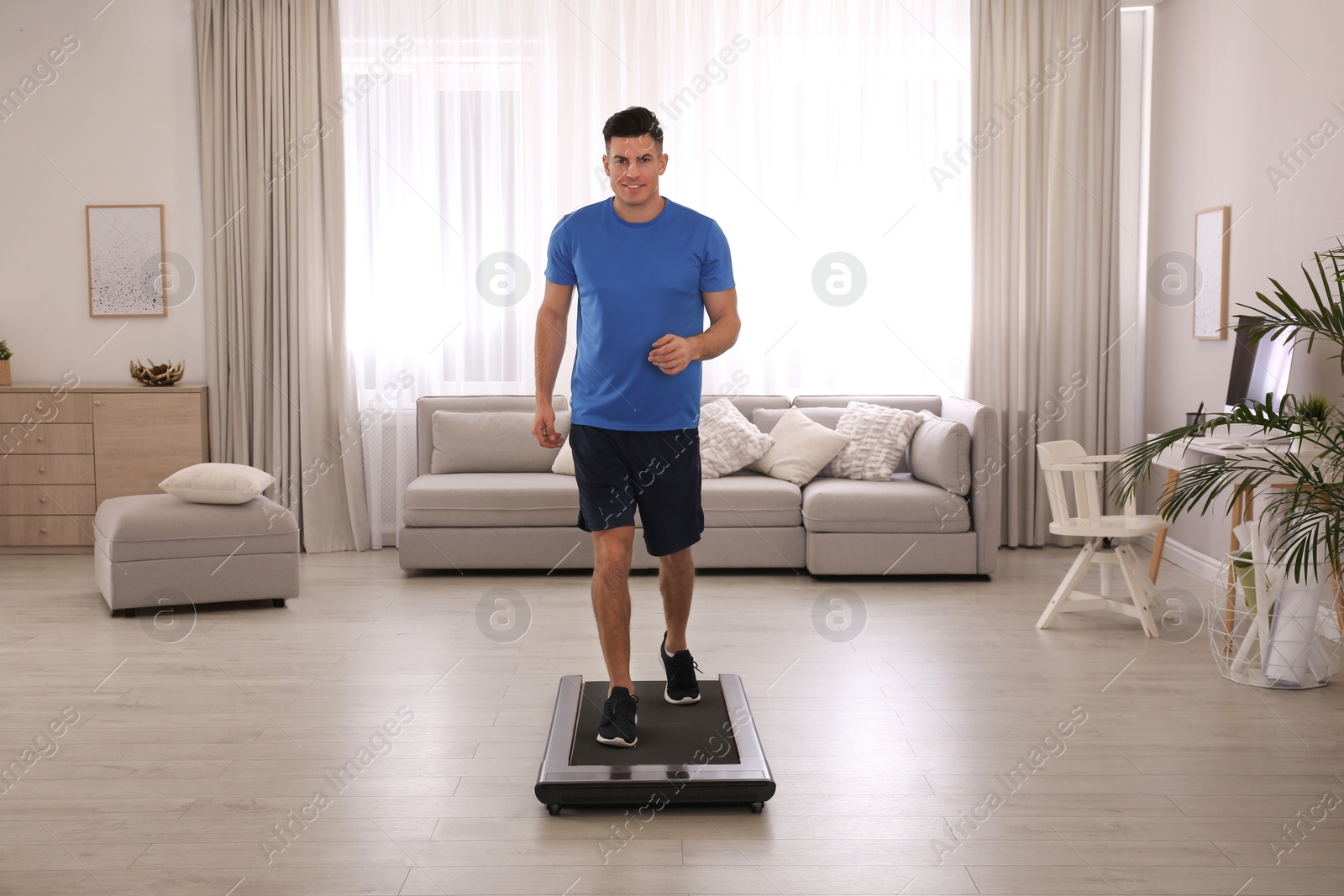 Photo of Sporty man training on walking treadmill at home