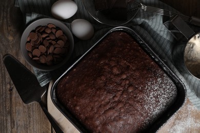 Photo of Homemade chocolate sponge cake and ingredients on wooden table, flat lay