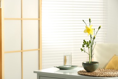 Stylish ikebana with beautiful yellow flowers carrying cozy atmosphere at home, space for text
