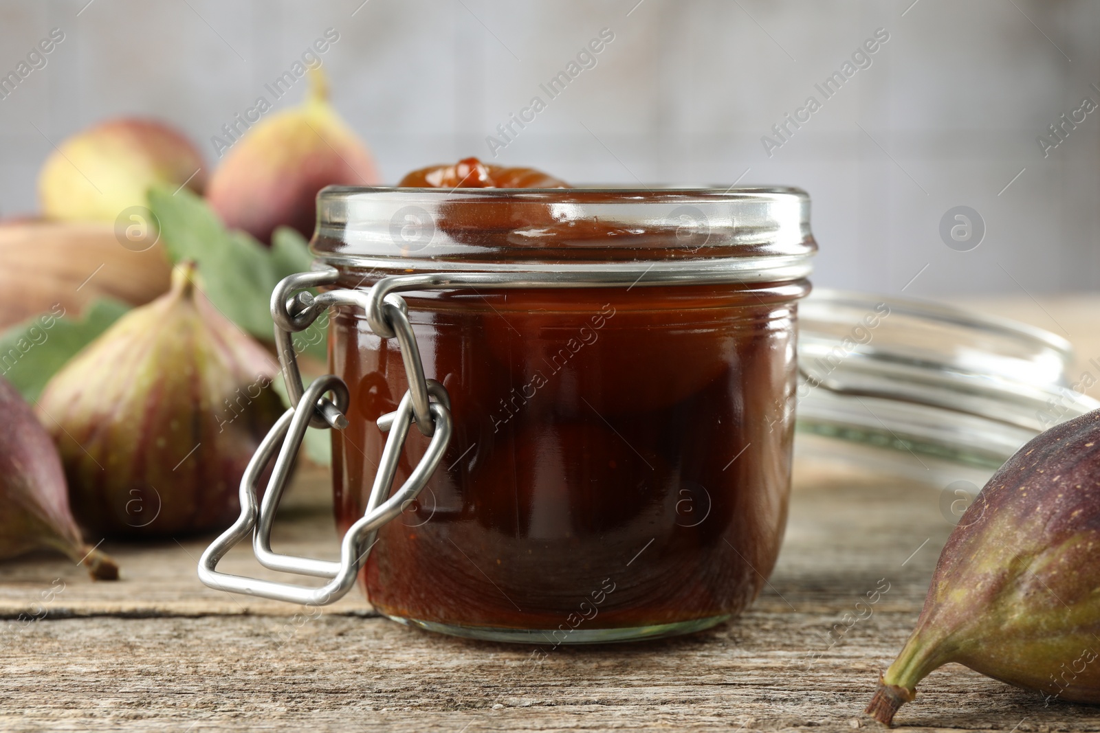 Photo of Jar of tasty sweet jam and fresh figs on wooden table