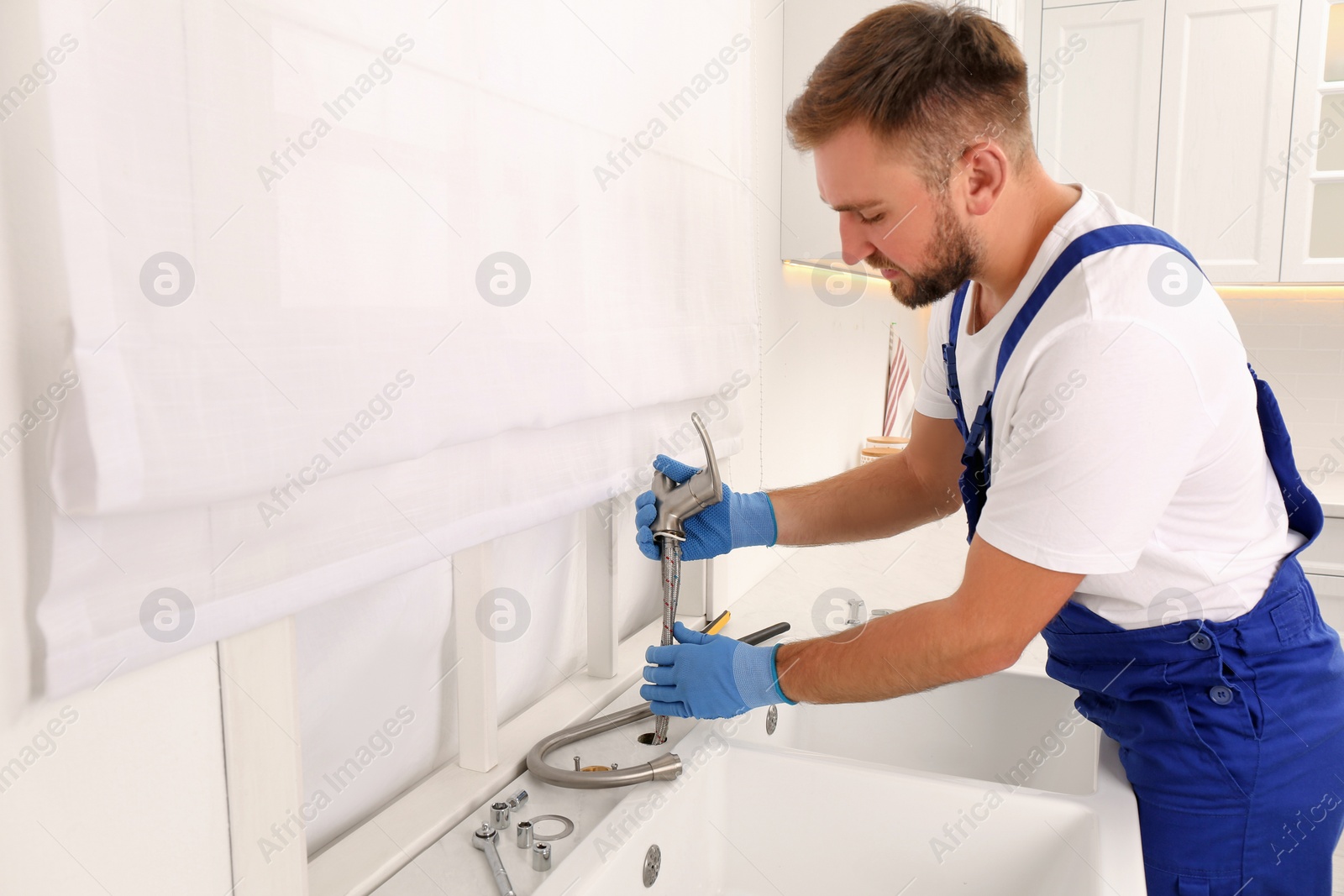 Photo of Professional plumber repairing water tap in kitchen