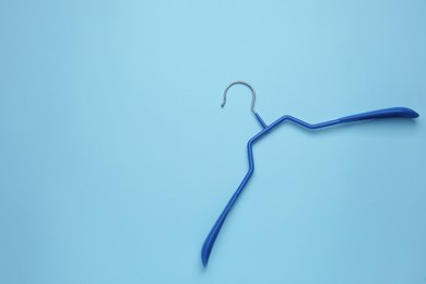 Photo of Empty clothes hanger on light blue background, top view. Space for text