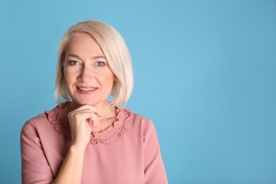 Portrait of charming mature woman with healthy beautiful face skin and natural makeup on blue background, space for text