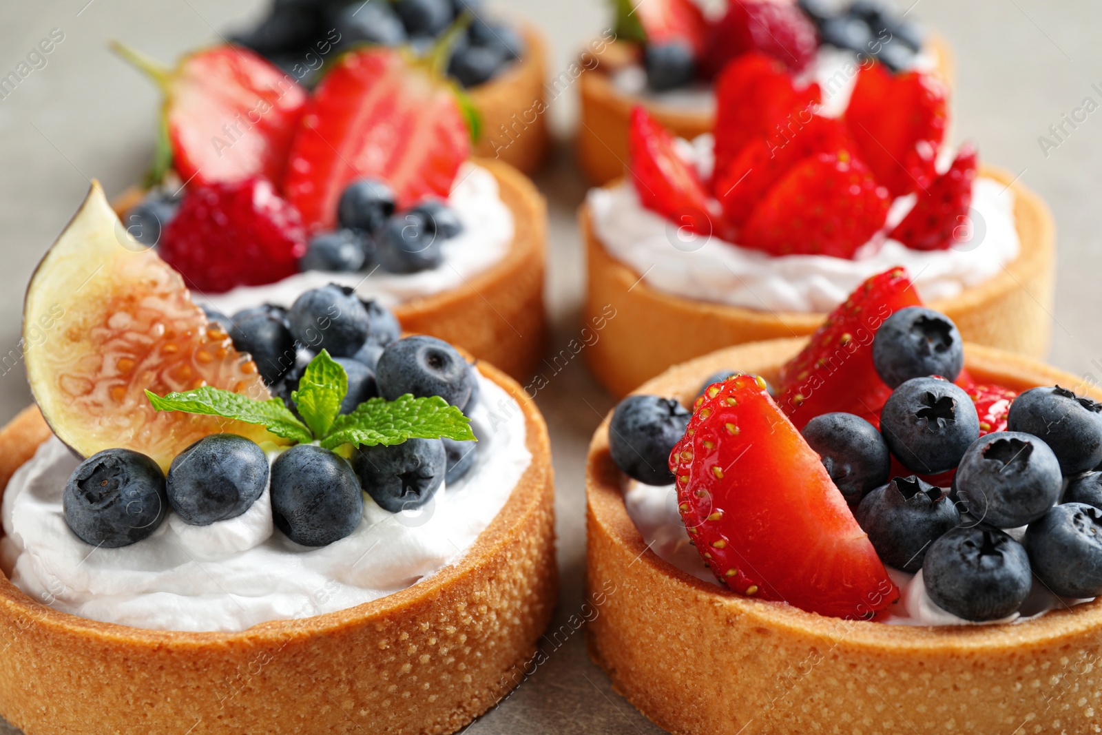 Photo of Delicious sweet pastries with berries on grey table, closeup