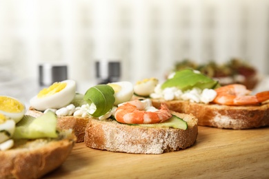 Cutting board of delicious bruschettas with shrimps on kitchen table