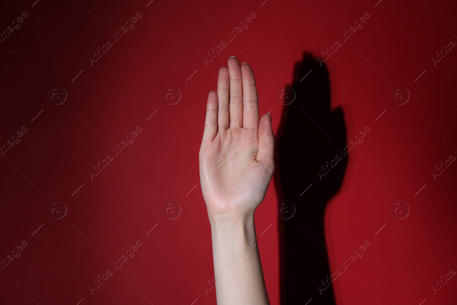 Photo of Woman showing open palm on red background, closeup