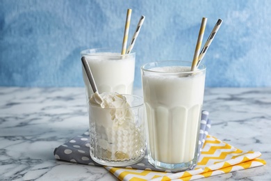 Glasses with milk shake and tasty vanilla ice cream on table