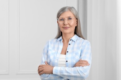 Portrait of beautiful senior woman in glasses indoors. Space for text