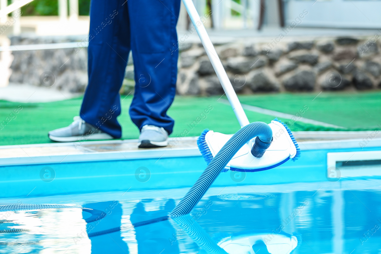 Photo of Male worker cleaning outdoor pool with underwater vacuum