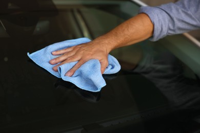 Photo of Man cleaning car windshield with rag, closeup