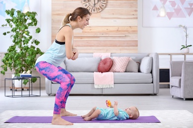 Young sportive woman doing exercise with her son at home, space for text. Fitness training