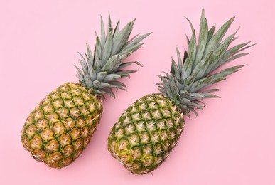 Delicious ripe pineapples on pink background, flat lay
