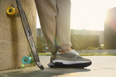 Photo of Man with skateboard wearing stylish sneakers outdoors, closeup