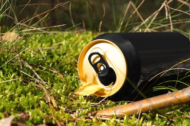 Photo of Used aluminium can on green grass outdoors, closeup. Recycling problem