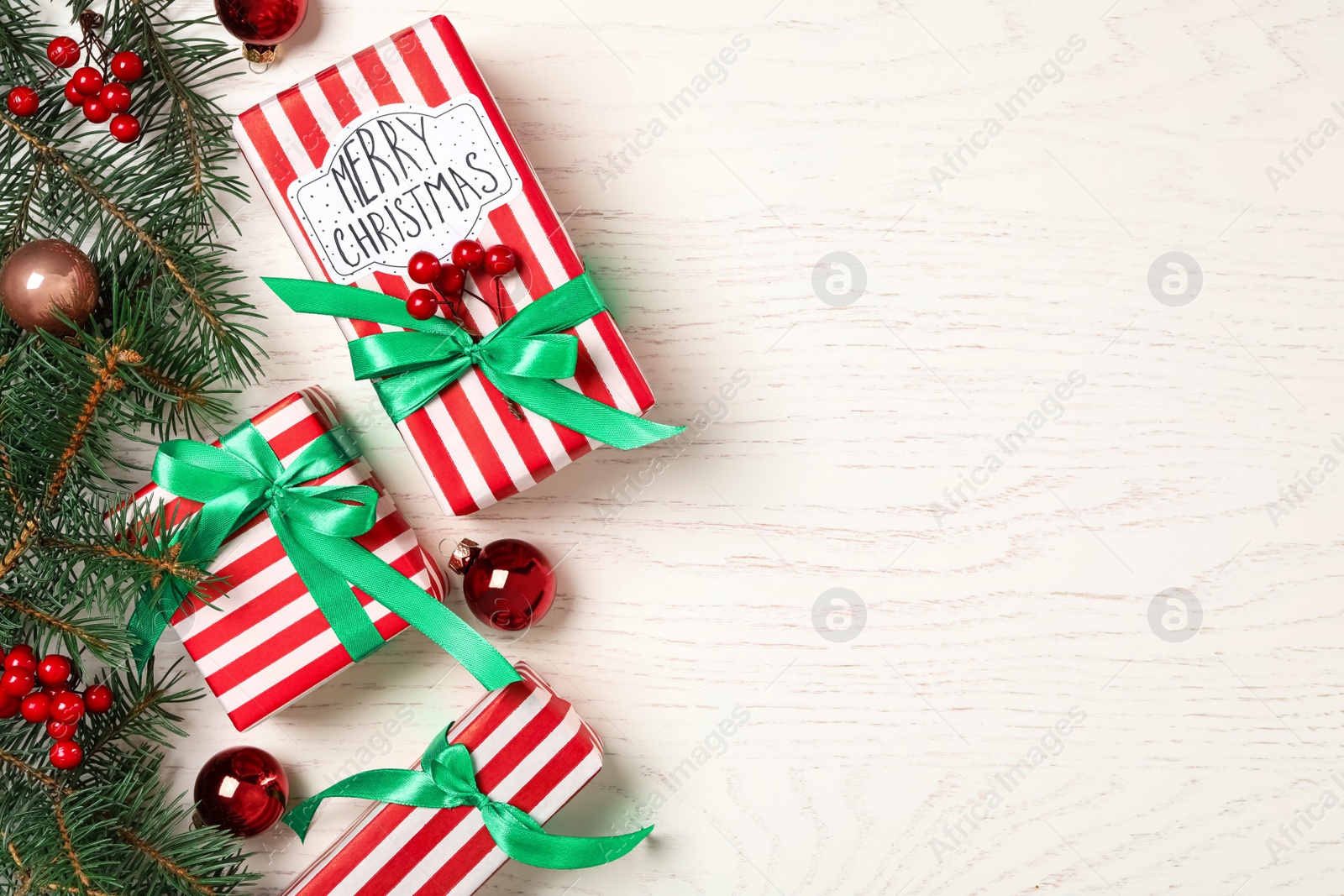 Photo of Flat lay composition with Christmas gift boxes and fir branches on white wooden background. Space for text