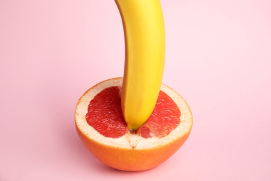 Fresh grapefruit and banana on pink background. Sex concept