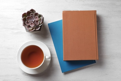 Photo of Flat lay composition with hardcover book and cup of tea on white wooden table
