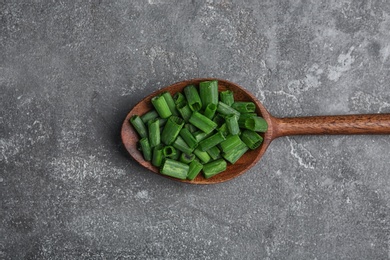 Photo of Spoon with chopped green onion on table, top view