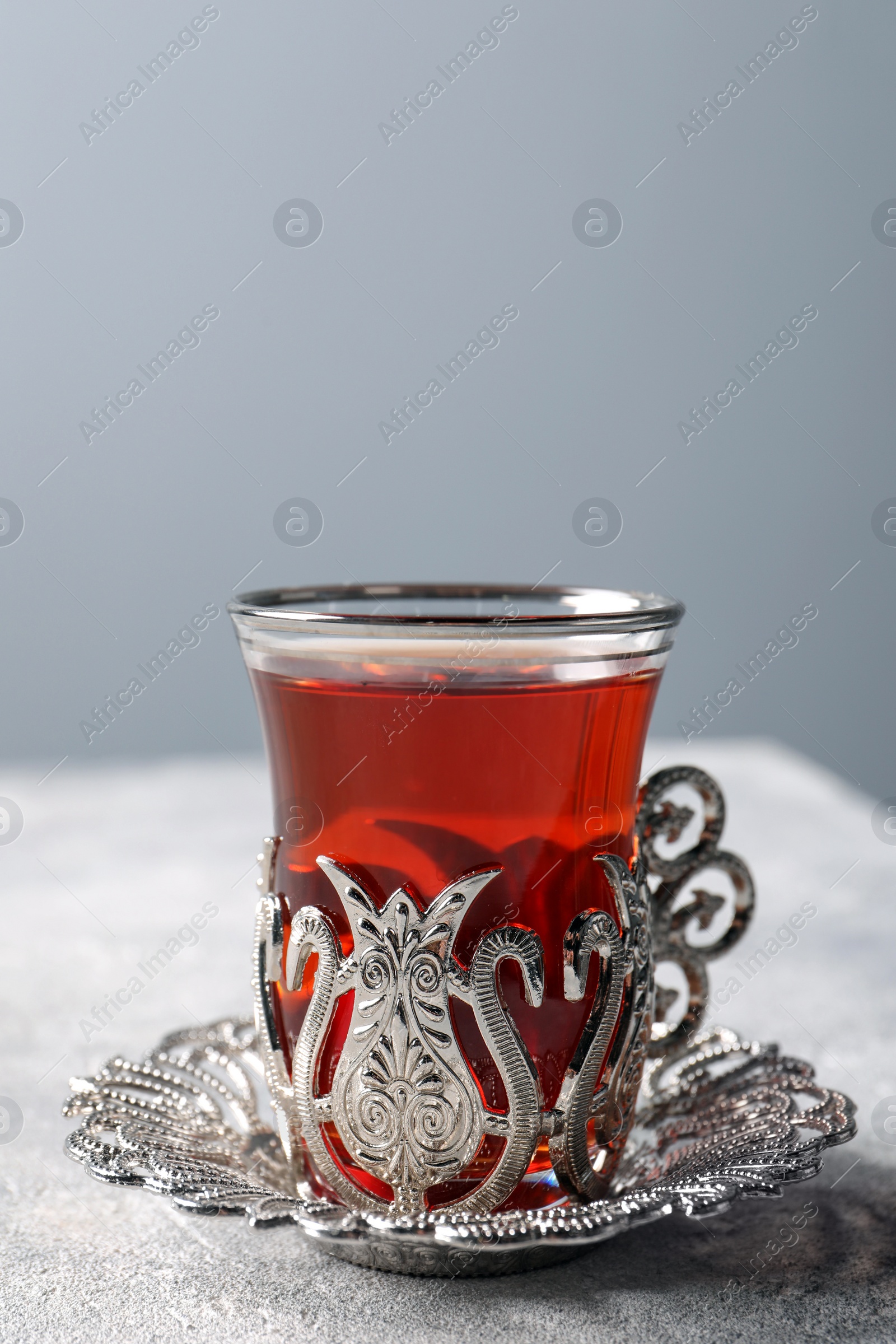 Photo of Glass of traditional Turkish tea in vintage holder on light grey table