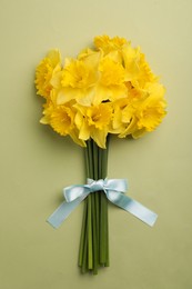 Photo of Beautiful daffodil bouquet on light green background, top view