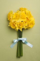 Beautiful daffodil bouquet on light green background, top view