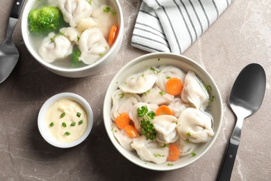 Tasty dumplings in broth served on grey marble table, flat lay