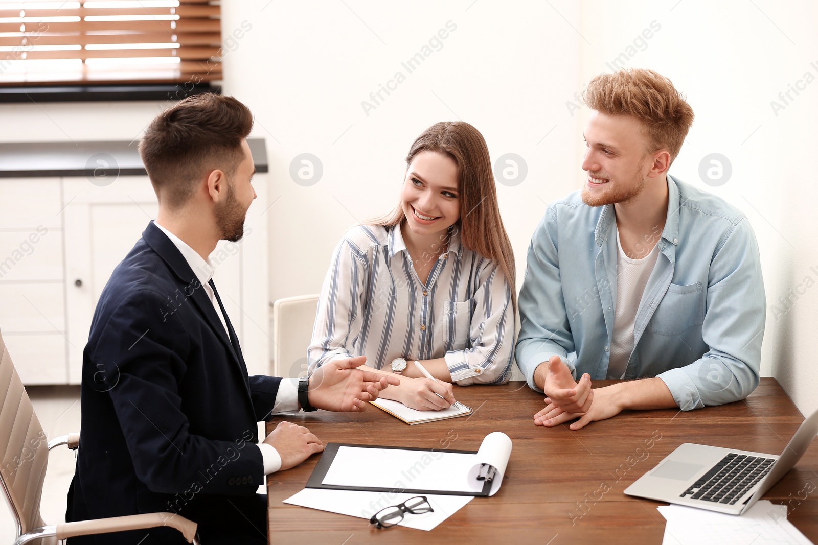 Photo of Insurance agent consulting young couple in office