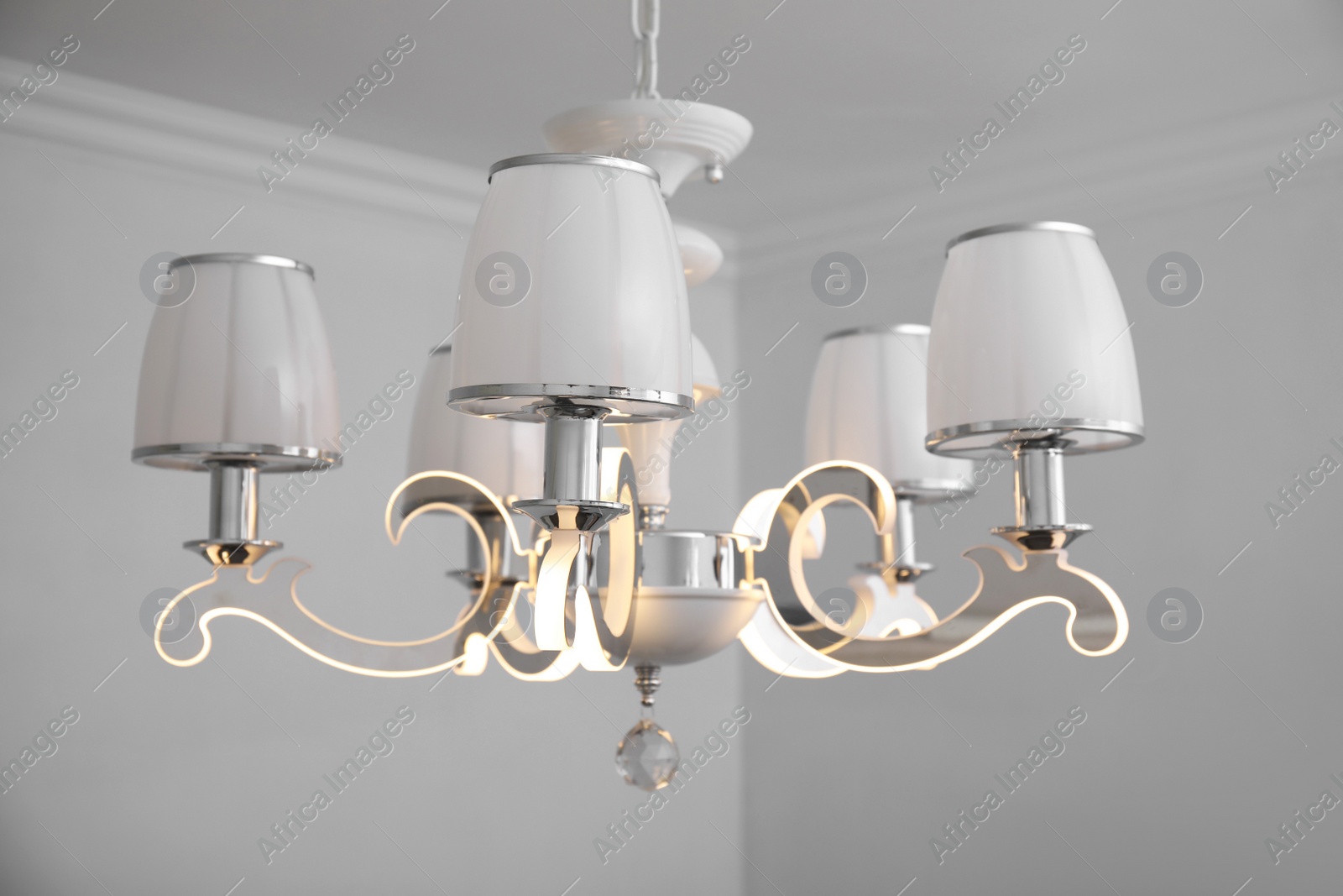 Photo of Stylish chandelier on ceiling in light room