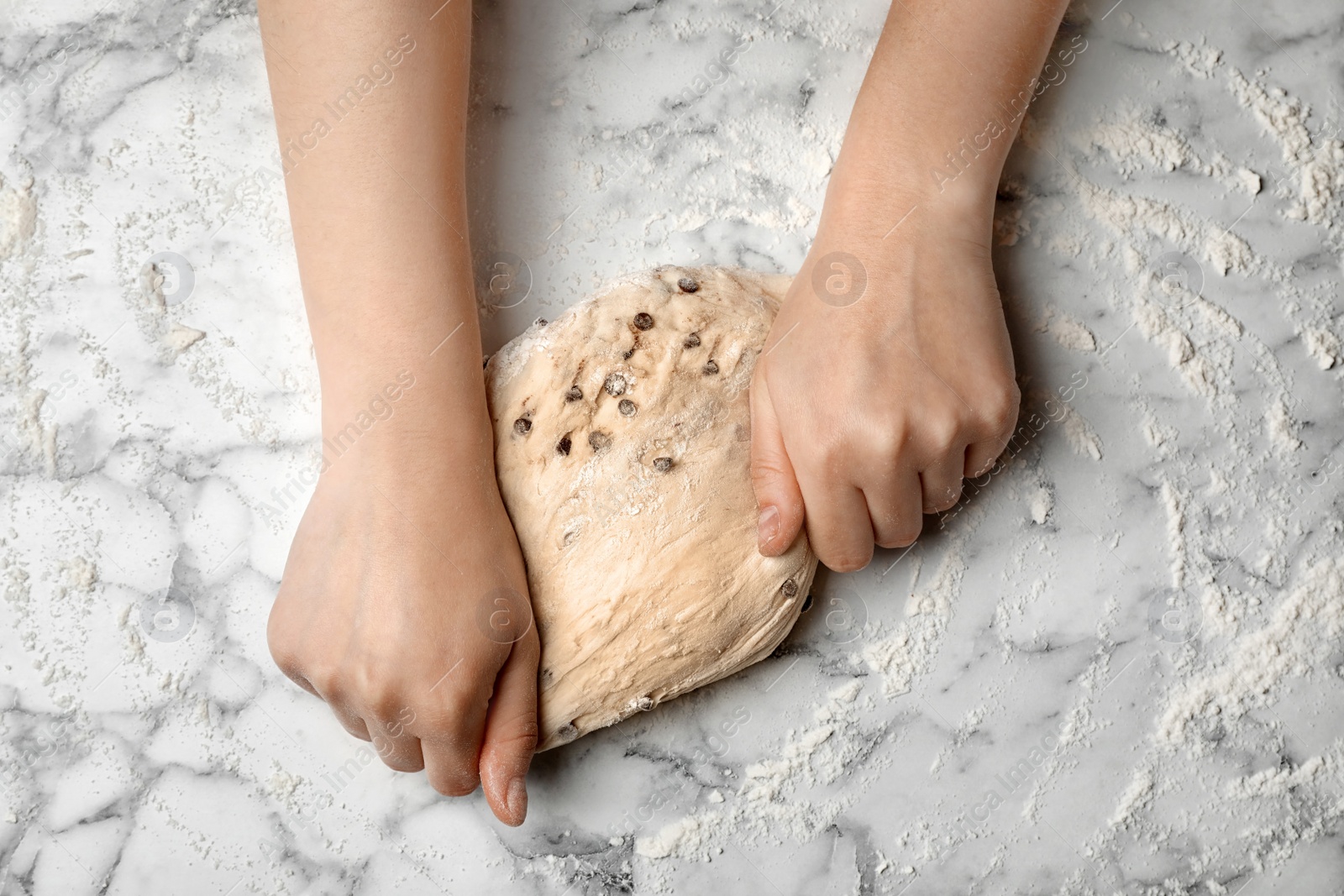 Photo of Young woman kneading dough at table, top view