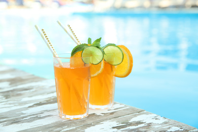 Refreshing cocktail in glasses near outdoor swimming pool on sunny day