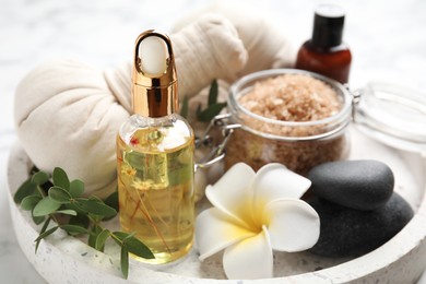 Photo of Beautiful spa composition with essential oil and plumeria flower on tray, closeup