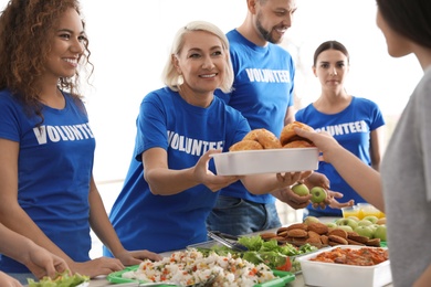 Volunteers serving food to poor people indoors