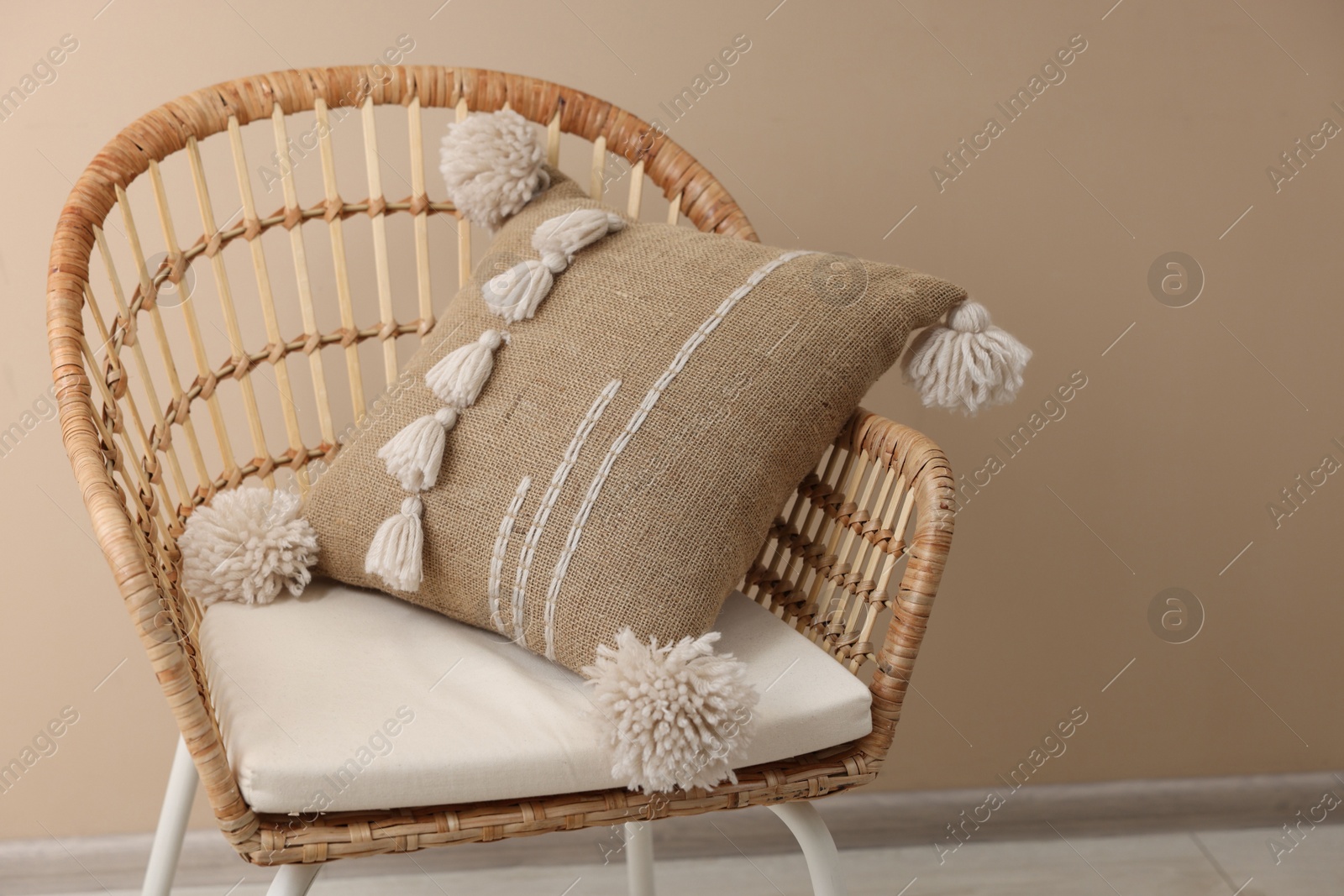 Photo of Stylish soft pillow on armchair near beige wall indoors. Space for text