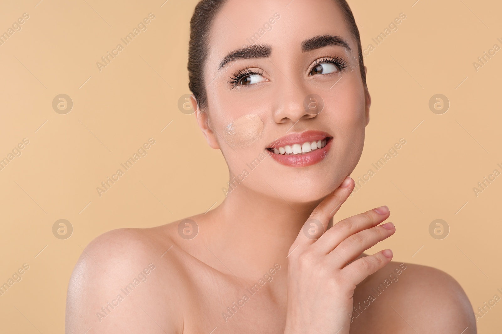 Photo of Woman with swatch of foundation on face against beige background