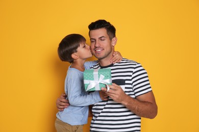 Photo of Man receiving gift for Father's Day from his son on yellow background