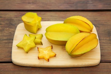 Photo of Cut and whole delicious ripe carambolas on wooden table